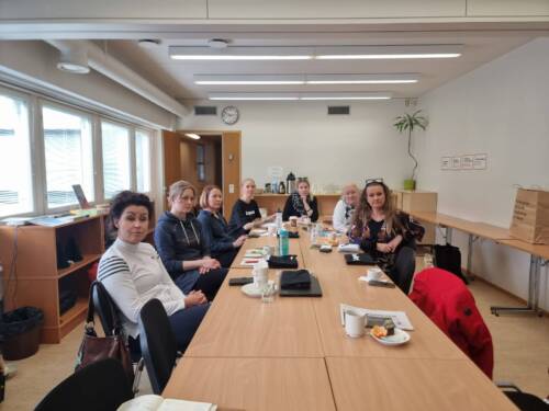 Ihmisiä istuu pitkän ruskean pöydän ympärillä